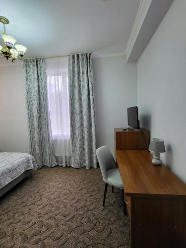 a bedroom with a bed and a desk and a television at Vila Verde in Chişinău