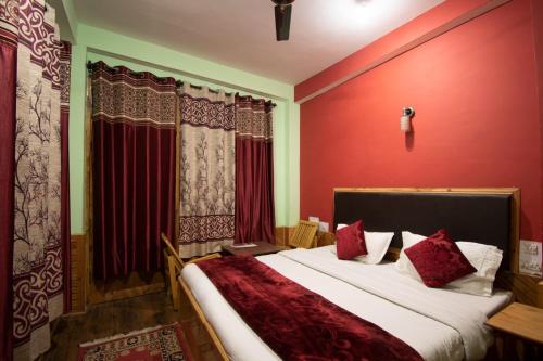 a bedroom with a large bed with red walls at Crystal Mountain Jibhi in Jibhi