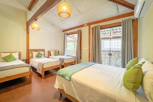 a hotel room with two beds and a window at VELINN Pousada Canoa Ilhabela in Ilhabela