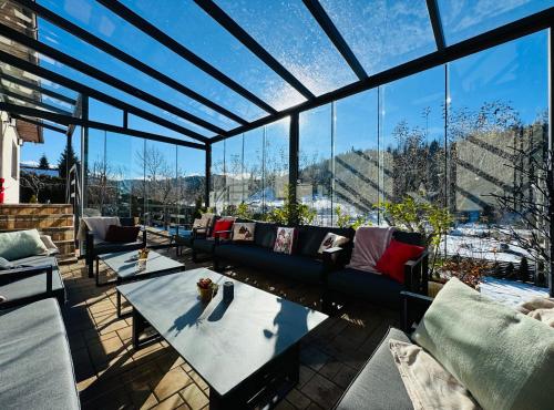 a living room with couches and tables and windows at Cazare Colibița Casa Lipan cu jacuzzi, foișor și loc de joacă in Colibiţa