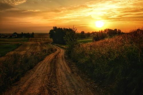 a dirt road with the sunset in the background at Apartament Suwałki Centrum Wesoła in Suwałki