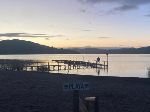 a sign on a beach with a pier in the water at Vichuquen Lodge y Marina in Vichuquén