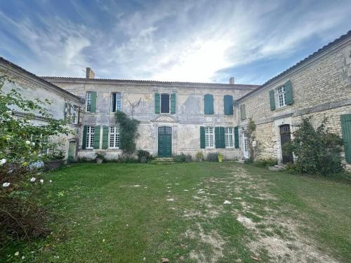a large stone building with green shutters and a yard at Maison Garesché - idéal télétravail & nature in Nieulle-sur-Seudre