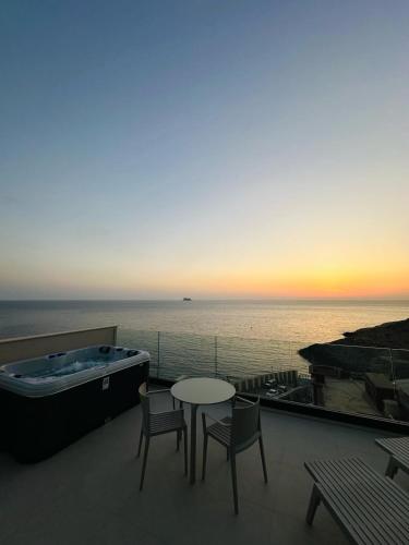 a balcony with a tub and a table and chairs at Deep Blu Boutique Hotel in Żurrieq