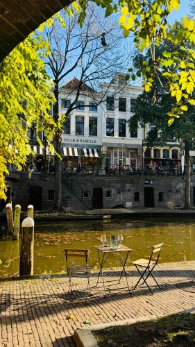 a table and chairs next to a river with a building at The Stork - In luxe logeren aan de Oudegracht, Centrum Utrecht in Utrecht