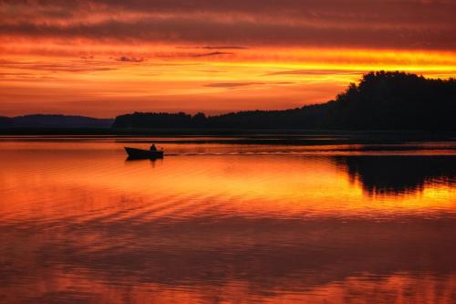 a person in a boat on a lake at sunset at Apartament Suwałki Centrum Wesoła in Suwałki