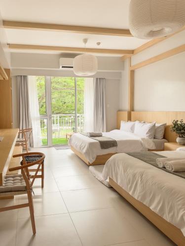 a bedroom with two beds and a large window at Yugen Suites at Pico De Loro in Nasugbu