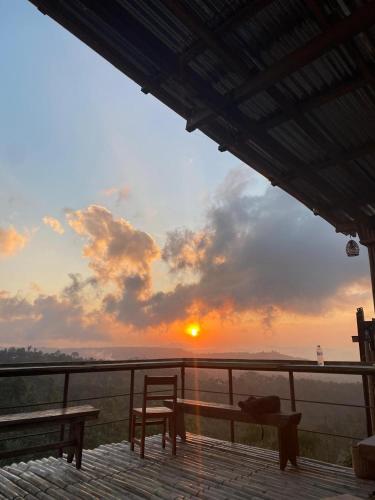 a sunset from a deck with a table and a chair at Wanagiri sunset glamping in Gitgit