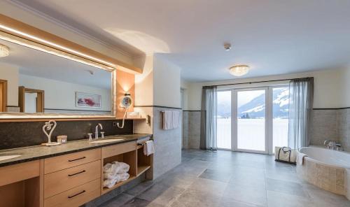 duża łazienka z wanną i umywalką w obiekcie Hotel Alpina Wellness & Spa Resort w mieście Kössen