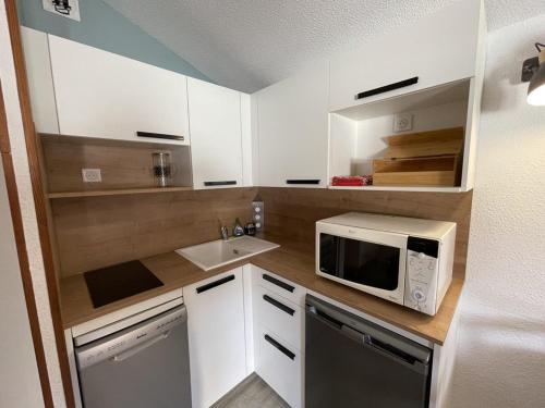 une petite cuisine avec un micro-ondes et un évier dans l'établissement Appartement fonctionnel 4.5 pers, proche pistes et commerces, balcon exposé Sud-Est - FR-1-787-82, à Laveissière