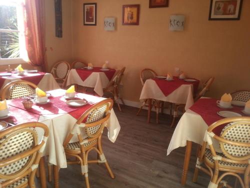 ein Esszimmer mit Tischen mit roten und weißen Tischdecken in der Unterkunft Hôtel La Résidence in Villeneuve-sur-Lot