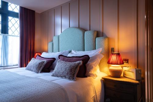 a bedroom with a large bed with a blue headboard at The Royal Forest - A Heartwood Inn in Chingford