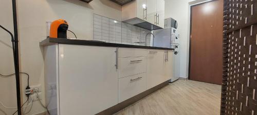 una cucina con armadi bianchi e un mobile arancione sul bancone di Trigoria Suite a Selcetta
