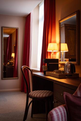 a hotel room with a desk and a mirror at The Royal Forest - A Heartwood Inn in Chingford