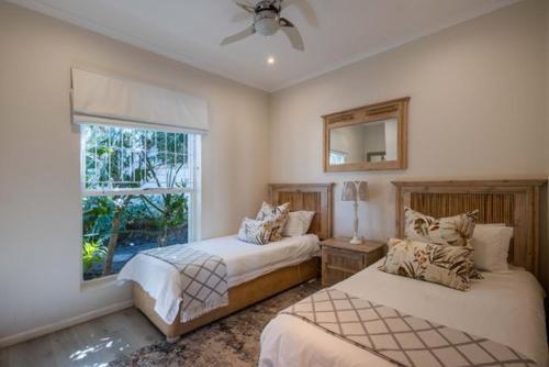 a bedroom with two beds and a window at 4198 River Club in Plettenberg Bay