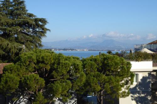 a view of the water with trees in the foreground at Catullo 18 Apartment, Garda Lake, Jacuzzi, Fitness, Ac in Desenzano del Garda