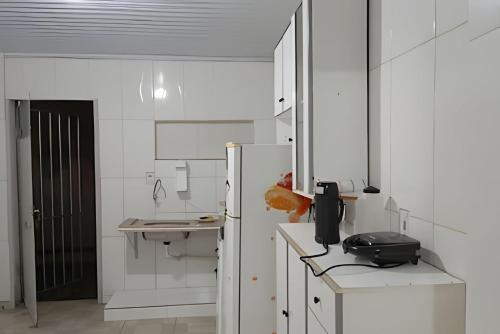 a white kitchen with a sink and a refrigerator at kitnet 01 preço popular in Brasília