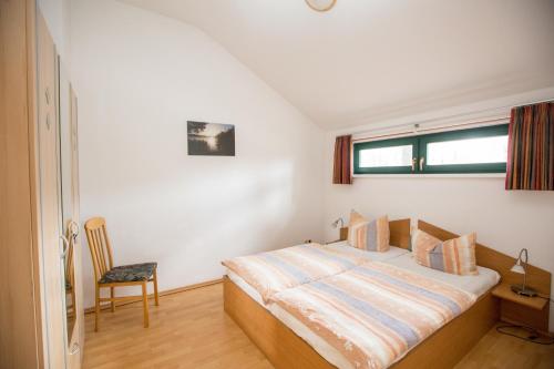 a bedroom with a bed and a chair and a window at Ferienhaus Waldschneise B am Jabeler See in Jabel