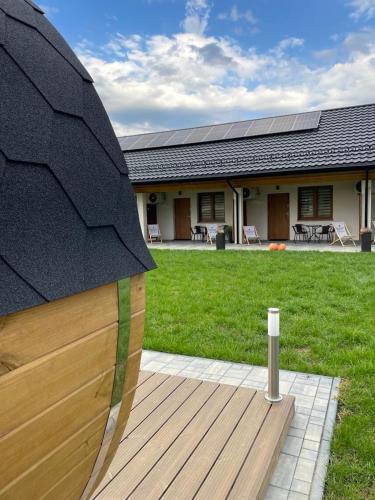 a house with a wooden deck with a yard at Leśne Apartamenty in Bobolice