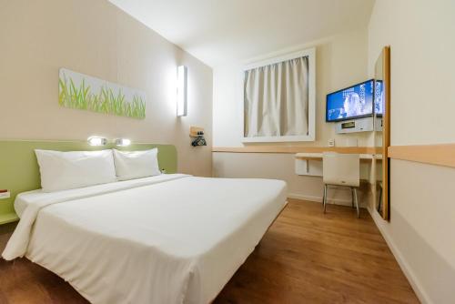 a bedroom with a large white bed and a desk at ibis budget Vitoria in Vitória