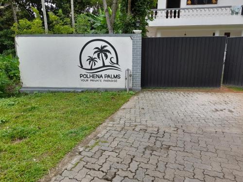 a sign for a house with a fence and a brick driveway at Polhena Palms in Polhena