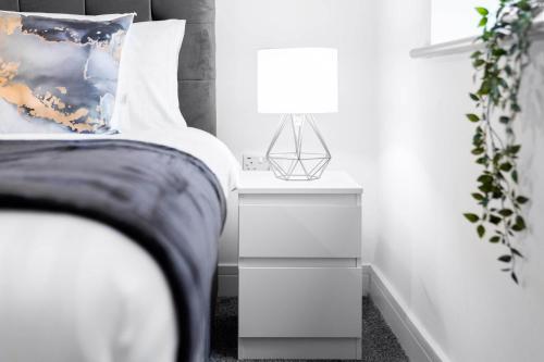 Un dormitorio con una cama y una mesita de noche con una lámpara. en Two Bedroom Apartment - Balcony - Secure Parking - Smart TV - Wifi - Netflix - 3MC, en Birmingham