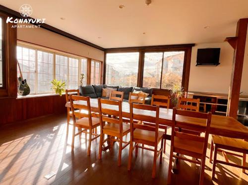 a dining room with a table and chairs and a couch at KONAYUKI Apartment in Myoko