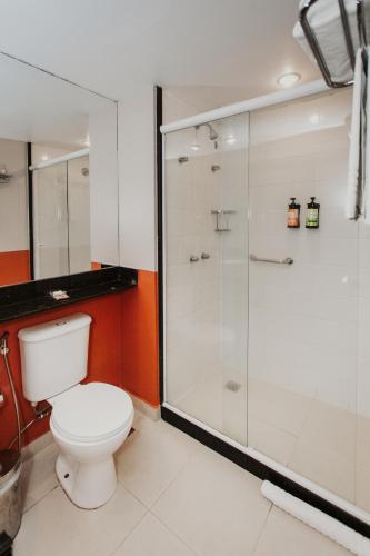 a bathroom with a toilet and a glass shower at Hotel Nacional Inn Angra dos Reis in Angra dos Reis
