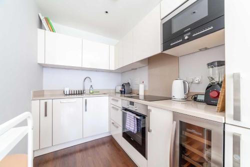 a kitchen with white cabinets and a sink at Cosy Central Urban Retreat in Highbury & Islington in London