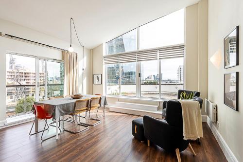 a living room with a table and chairs and a large window at Bright and Stylish Riverside Haven in Canary Wharf in London