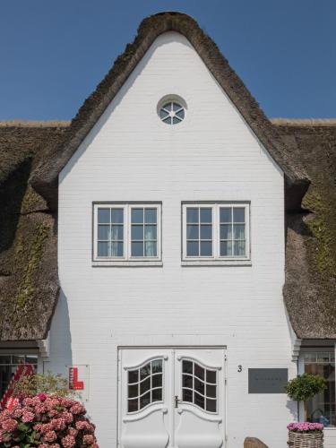 a white house with a thatched roof at Alte Mühle direkt am Wattenmeer in Keitum