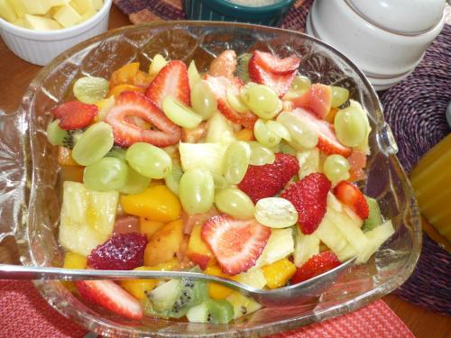 a bowl of fruit salad with a spoon in it at A1 Kynaston Guest House bed and breakfast or self catering in Jeffreys Bay