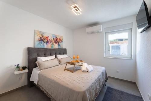 a bedroom with a bed with a table on it at Vila MaMe apartman s privatnim bazenom, besplatnim parkingom i wi - fi in Kaštela