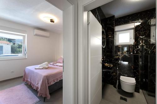 a bedroom with a bed and a bathroom with a window at Vila MaMe apartman s privatnim bazenom, besplatnim parkingom i wi - fi in Kaštela