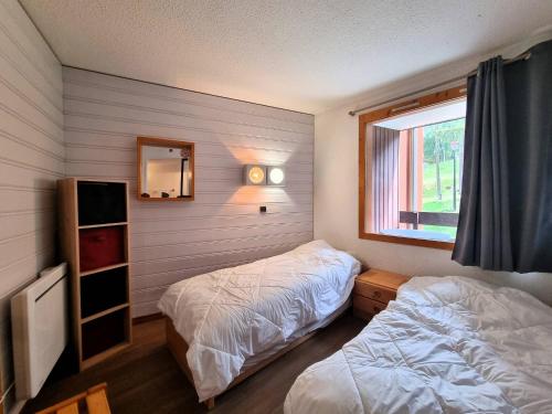 une chambre avec deux lits et une fenêtre dans l'établissement Appartement chaleureux 2 étoiles, animaux acceptés, proche pistes - FR-1-353-95, à La Plagne Tarentaise