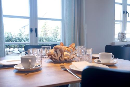 a wooden table with a bowl of food on it at NEU! Ferienhaus Litj Horsa Hoog - Luxus, Lage, Leichtigkeit mit Wellenrauschen in Wenningstedt Sylt in Wenningstedt