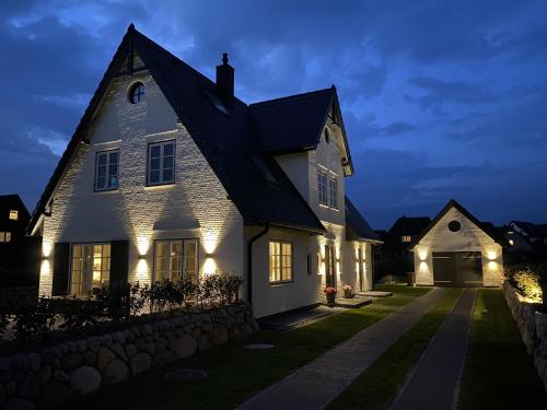 a white house with lights on it at night at NEU! Ferienhaus Litj Horsa Hoog - Luxus, Lage, Leichtigkeit mit Wellenrauschen in Wenningstedt Sylt in Wenningstedt
