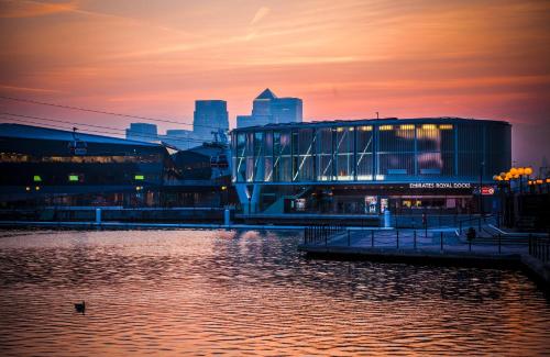a city skyline at sunset with a river and a building at Austin David Apartments ExCeL in London