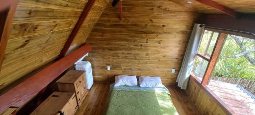 a small room with a bed in a wooden cabin at Chalé Paineira in Córrego do Bom Jesus