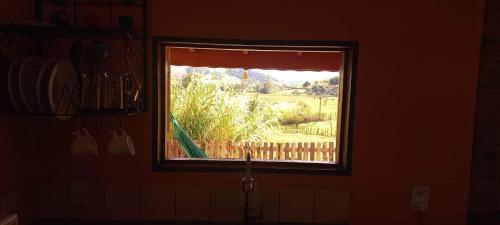 a window in a kitchen with a view of a yard at Chalé Paineira in Córrego do Bom Jesus