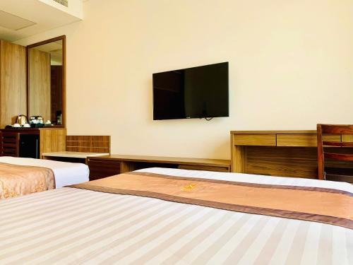 a hotel room with two beds and a flat screen tv at Lenid Ocean View Hotel in Nha Trang