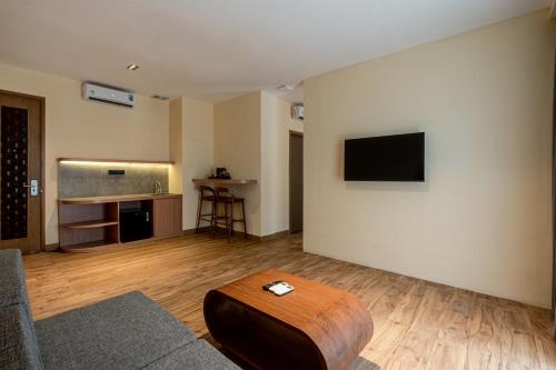 a living room with a couch and a tv on a wall at The Rivavi Legian in Legian
