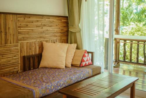 a couch sitting in a room with a window at Ban Sainai Resort- Aonang's Green Resort in Ao Nang Beach
