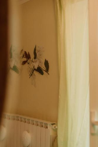 a bathroom with a curtain and flowers on the wall at Guesthouse Giulietta e Romeo in Cossogno