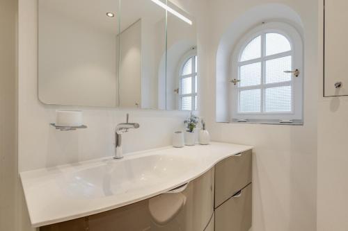 a white bathroom with a sink and a mirror at Ferienwohnung Waterkant in Munkmarsch