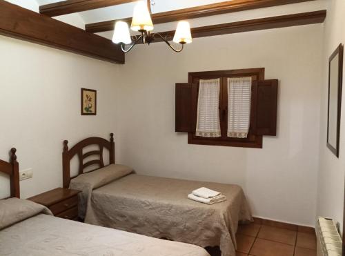 a bedroom with two twin beds and a window at Casa la Cisterna in Pina de Montolgrao