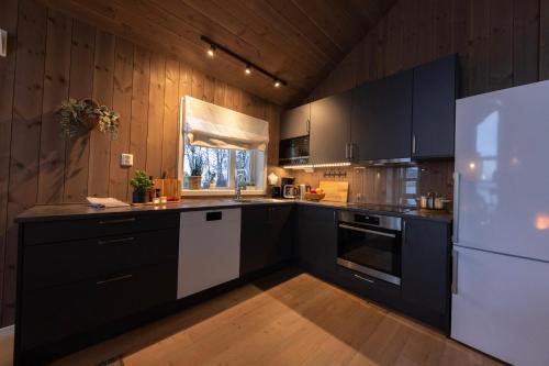 a kitchen with black cabinets and a white refrigerator at Holiday cabins with unmatched lake view in Jølster in Skei 