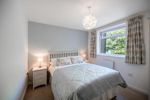 a white bedroom with a bed and a window at Fabulous Sea View Apartment in Aberdyfi