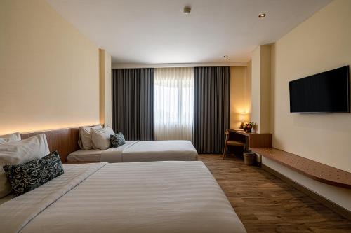 a hotel room with two beds and a flat screen tv at The Rivavi Legian in Legian