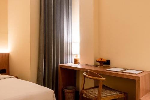 a bedroom with a desk with a bed and a bedskirts at The Rivavi Legian in Legian